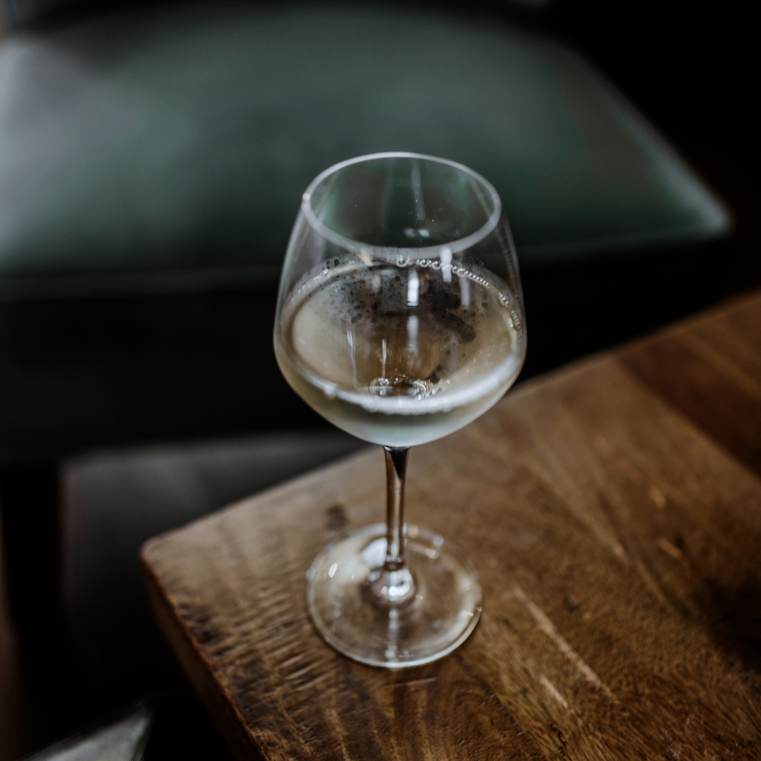 Image of dark academia photo of a wine glass for The Archive, a bookstore, coffee shop, and wine bar in Mount Pleasant, South Carolina.