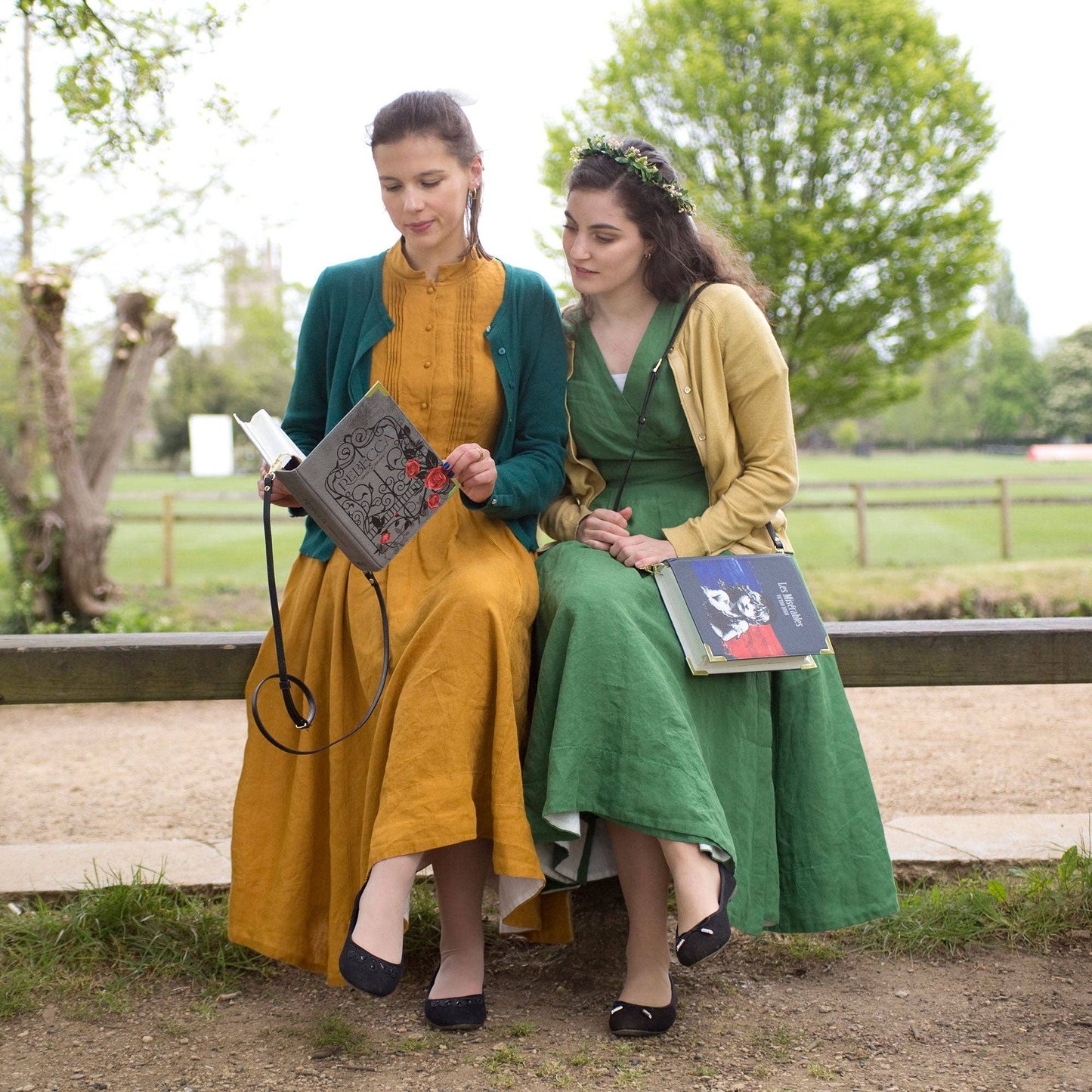 Two women in vintage-style clothing sitting on a bench outdoors.