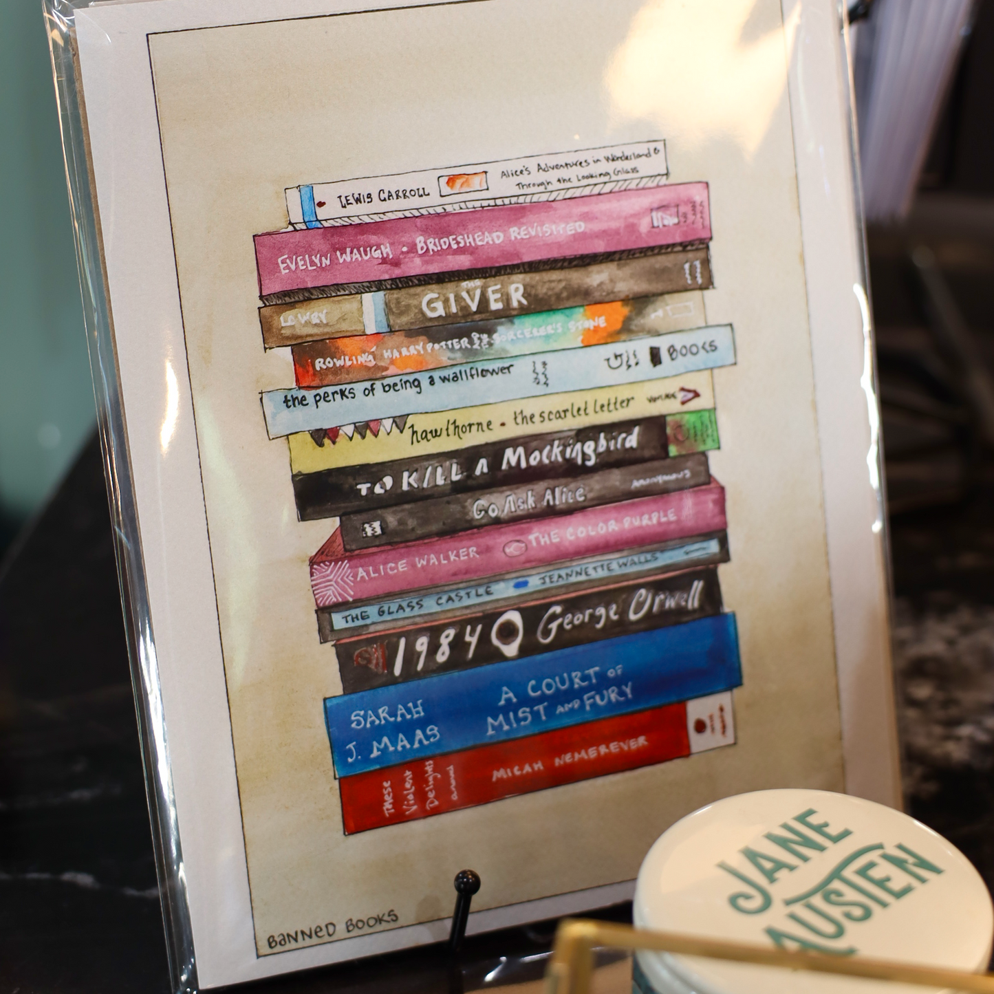 Framed artwork of books with visible text, placed on a surface.