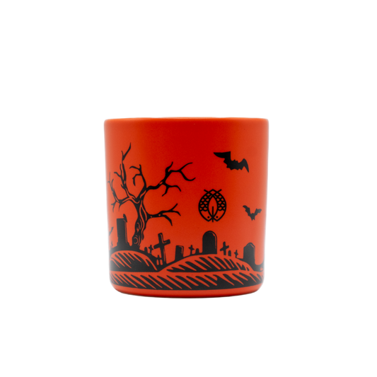 Orange candle with black Halloween-themed design on a white background