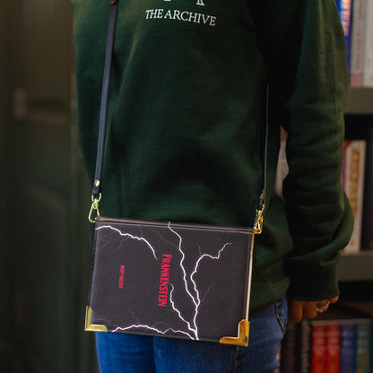 Person wearing a green hoodie with 'The Archive' logo, holding a black crossbody bag.
