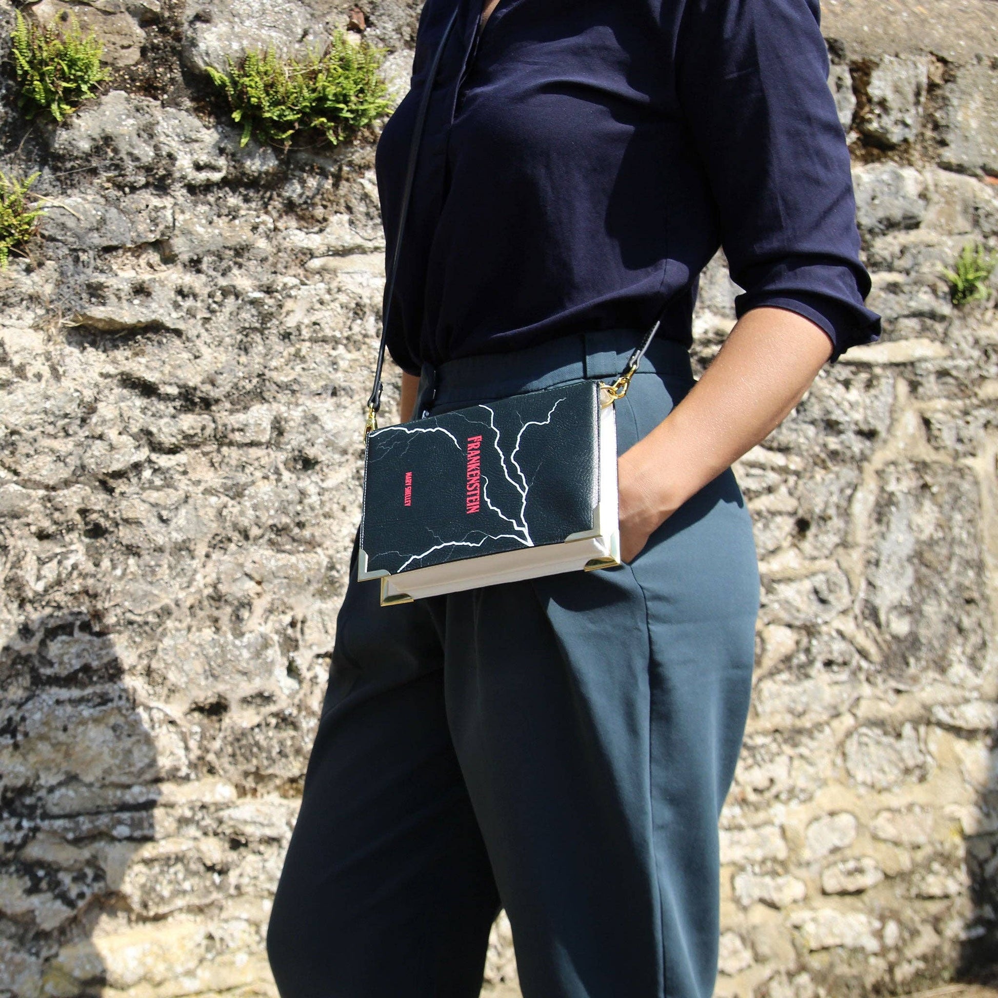 Person holding a book with a stone wall background