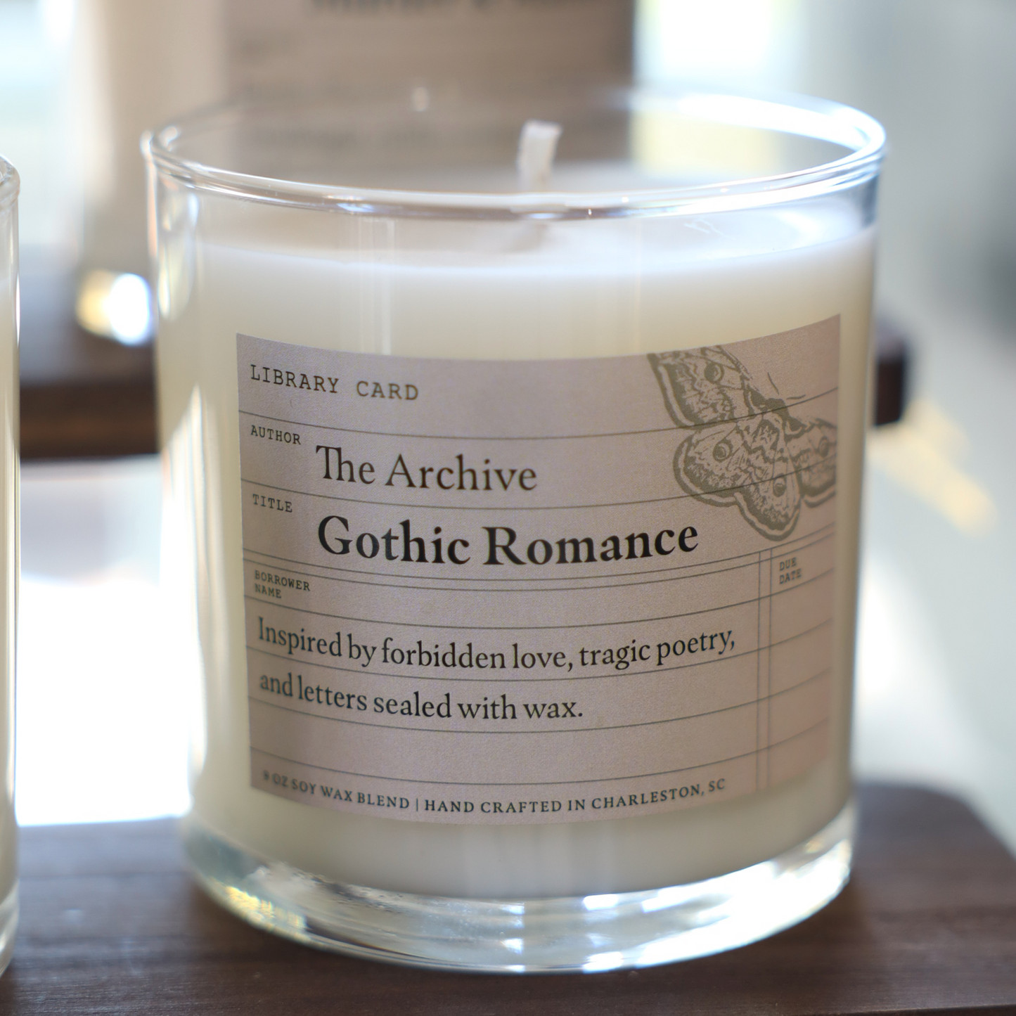 Candle labeled 'The Archive Gothic Romance' on a wooden surface