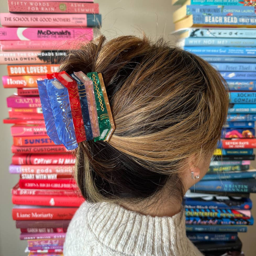 Person with colorful hair clips in front of stacked books