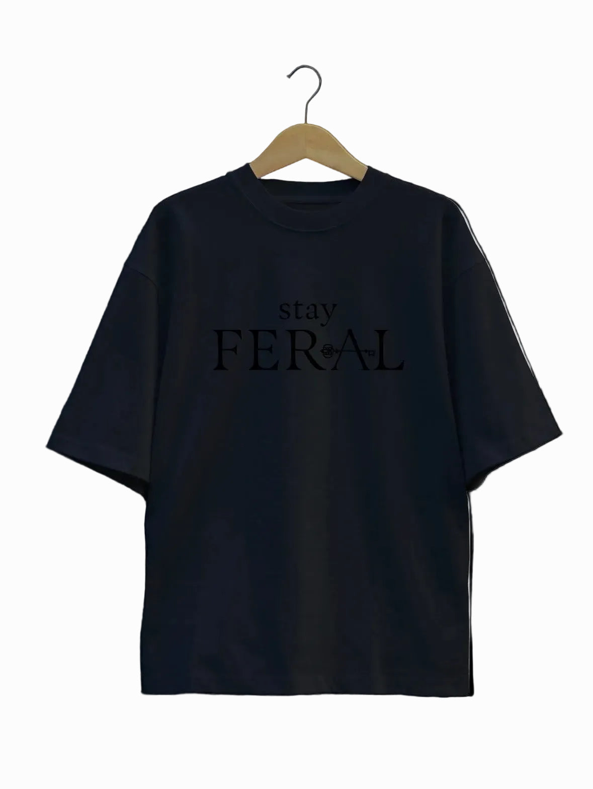 Black t-shirt with 'stay FERAL' text on a hanger against a light gray background