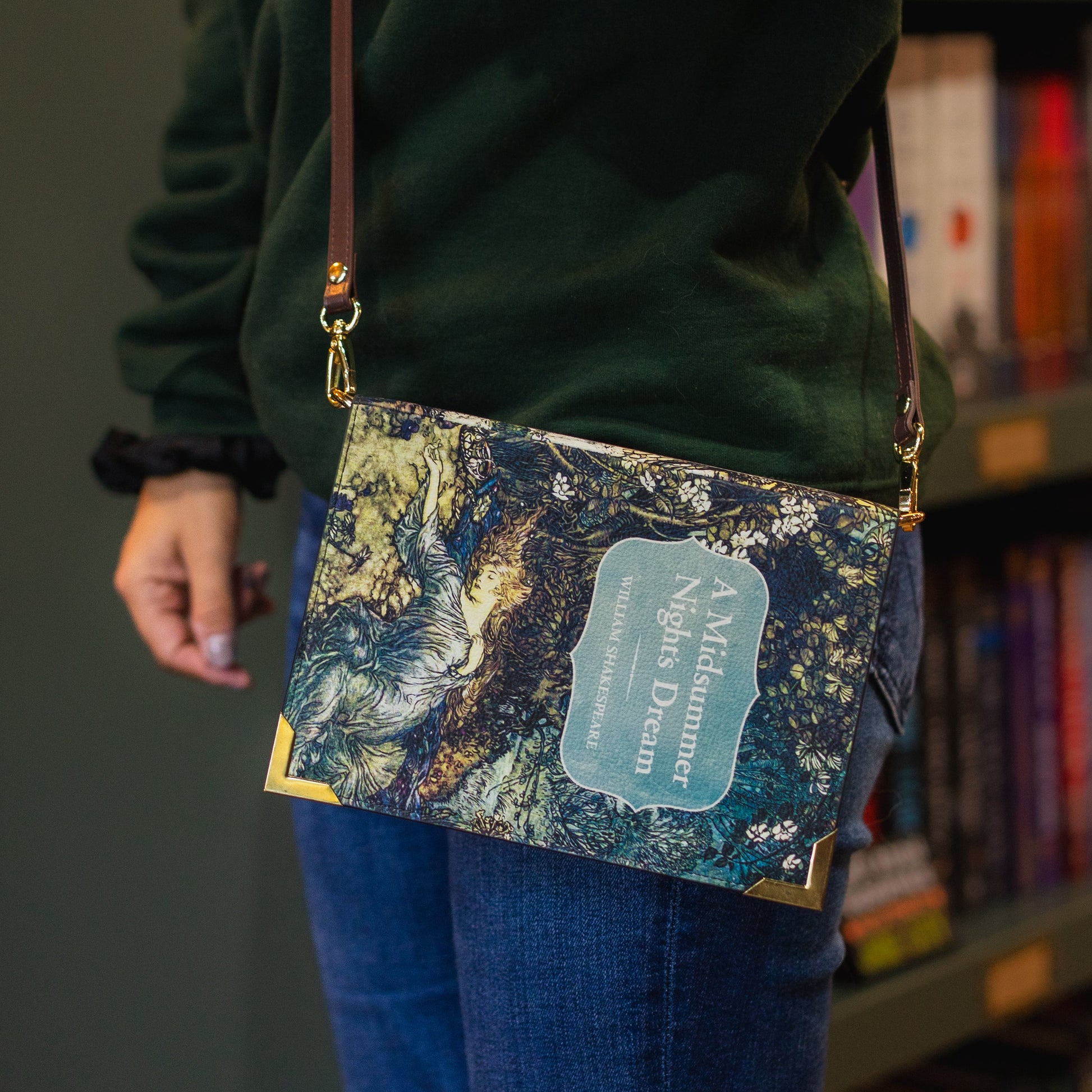 Person wearing a crossbody bag with a nature-themed design in front of a bookshelf.