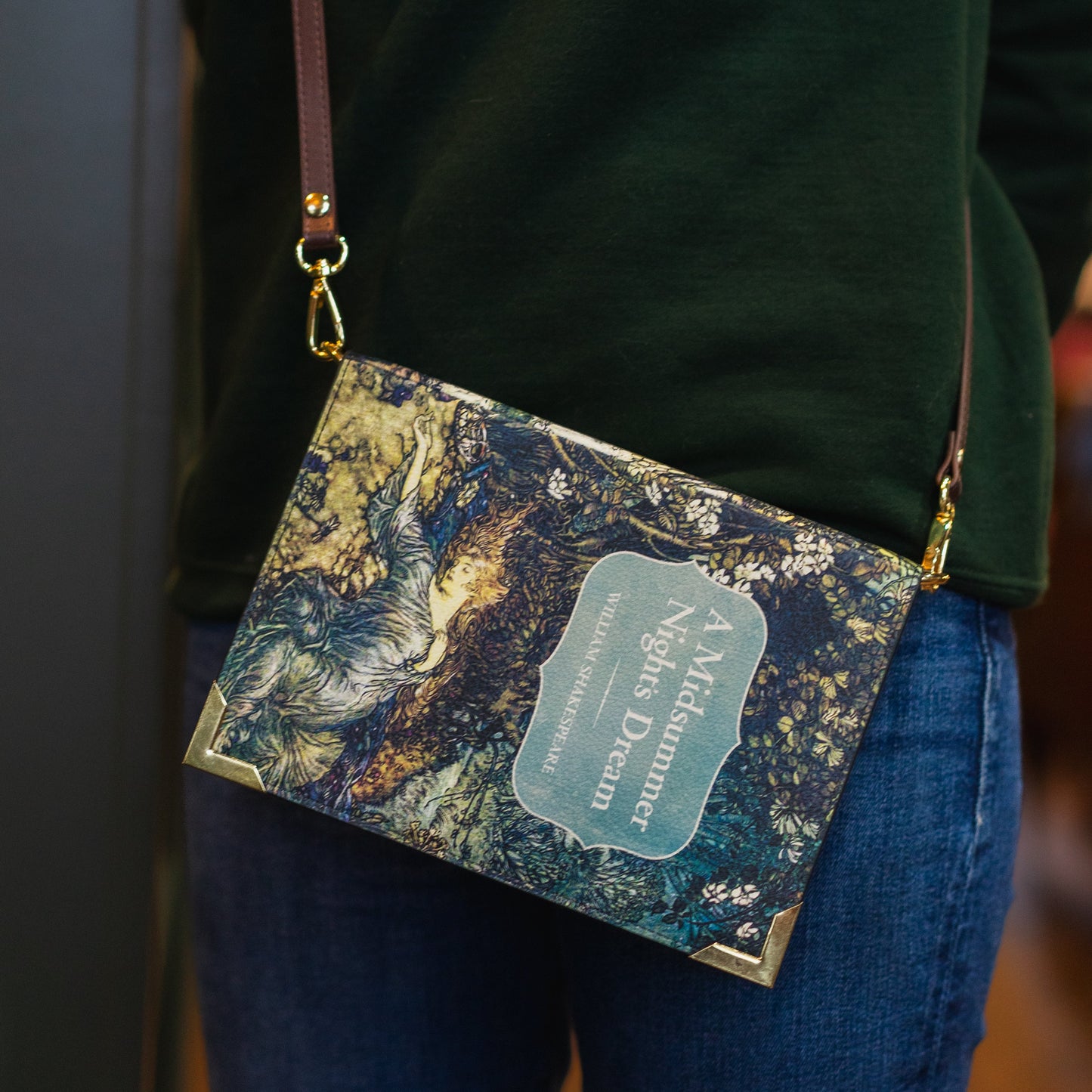Marbled patterned handbag with a visible brand name held by a person wearing a green sweater and blue jeans.