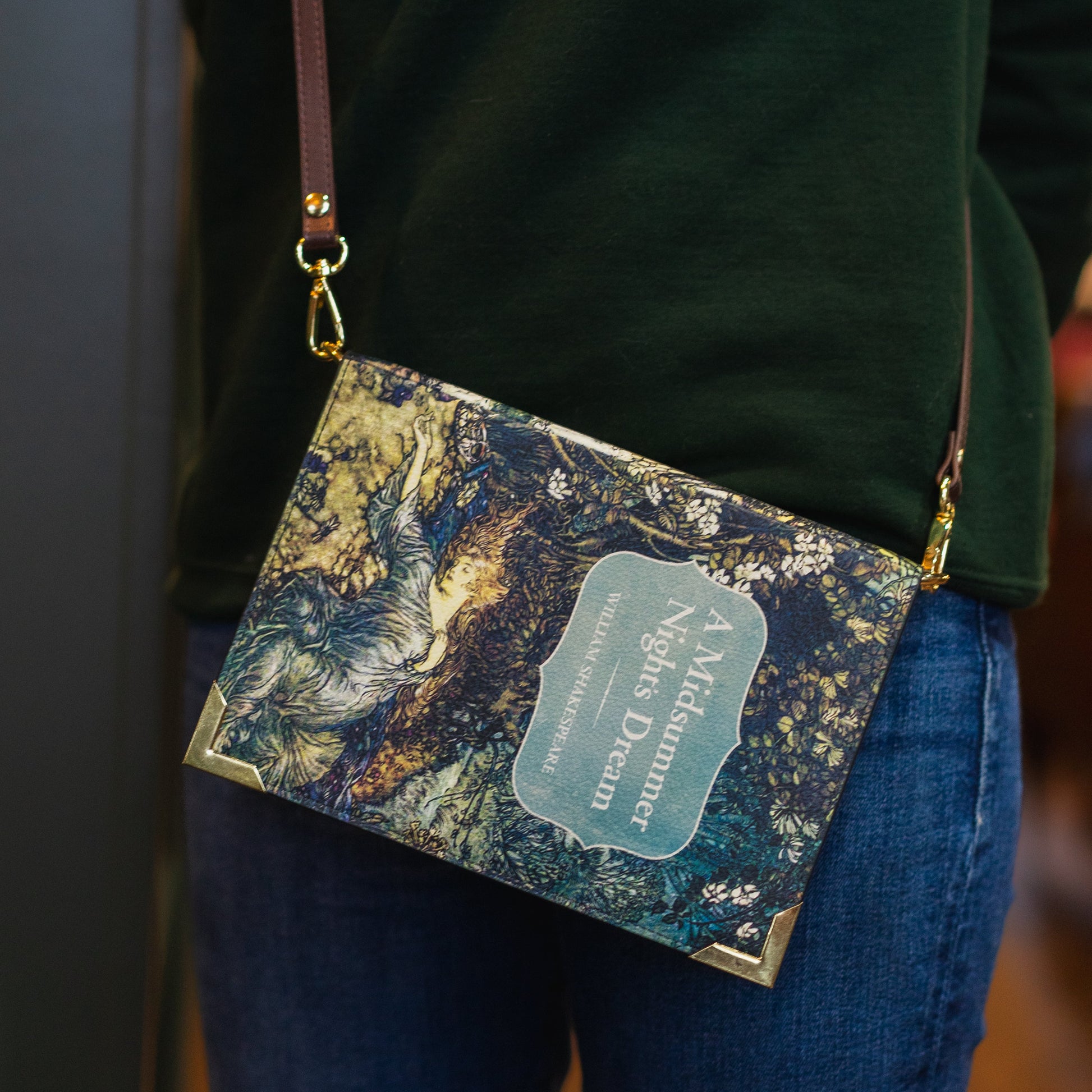 Marbled patterned handbag with a visible brand name held by a person wearing a green sweater and blue jeans.