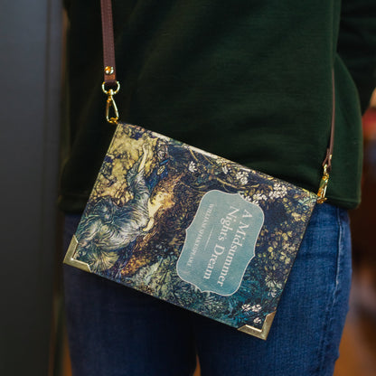 Marbled patterned handbag with a visible brand name held by a person wearing a green sweater and blue jeans.