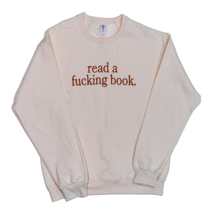 Beige sweatshirt with text 'read a fucking book' on a white background