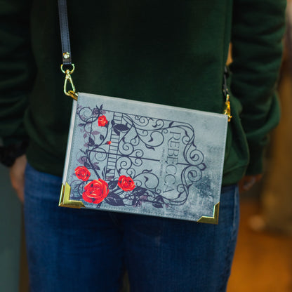Person wearing a green sweater with a decorative bag featuring red flowers and intricate designs.