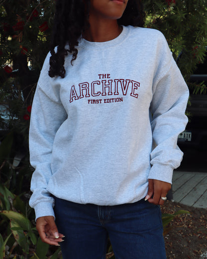 Person wearing a light gray sweatshirt with red text outdoors