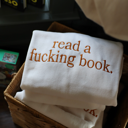 Stack of white shirts with text in a wicker basket on a dark surface